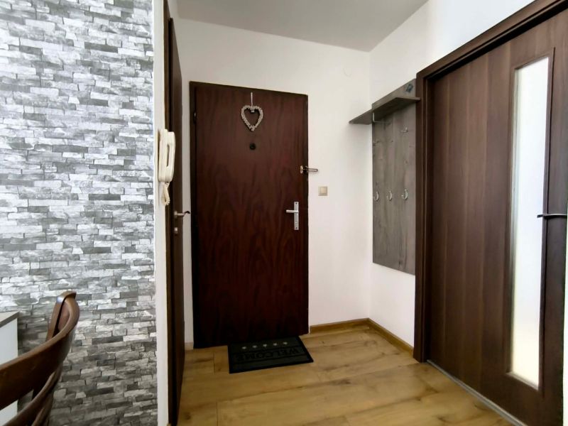 Entrance hallway in a 3-room apartment with a wooden decor floor and stone wall cladding.