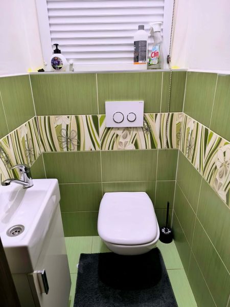Bathroom in a 3-room apartment with a toilet, green tiles, and a sink.
