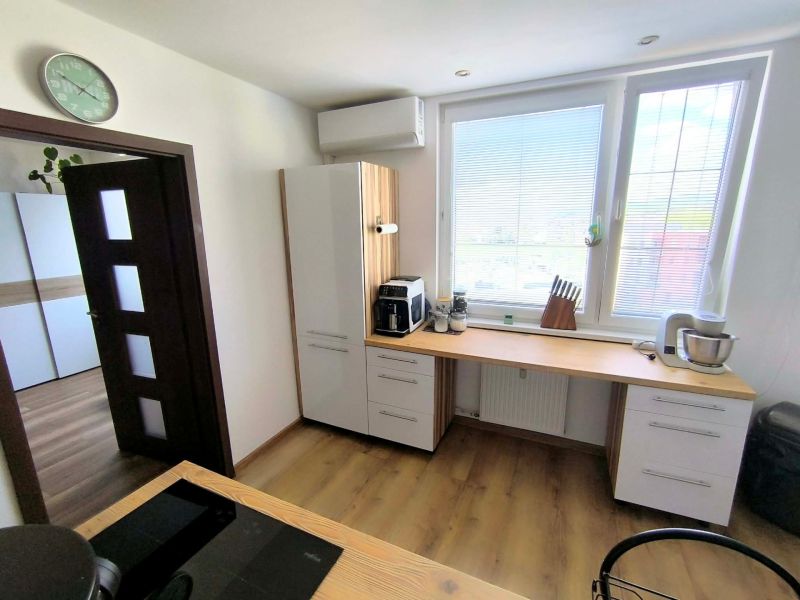 A kitchen in a 3-room apartment with light cabinets and a wooden-patterned floor.
