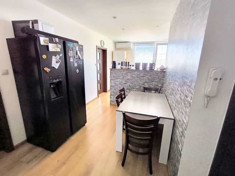 A kitchen with a dining table and a wall with stone decor in a 3-room apartment.