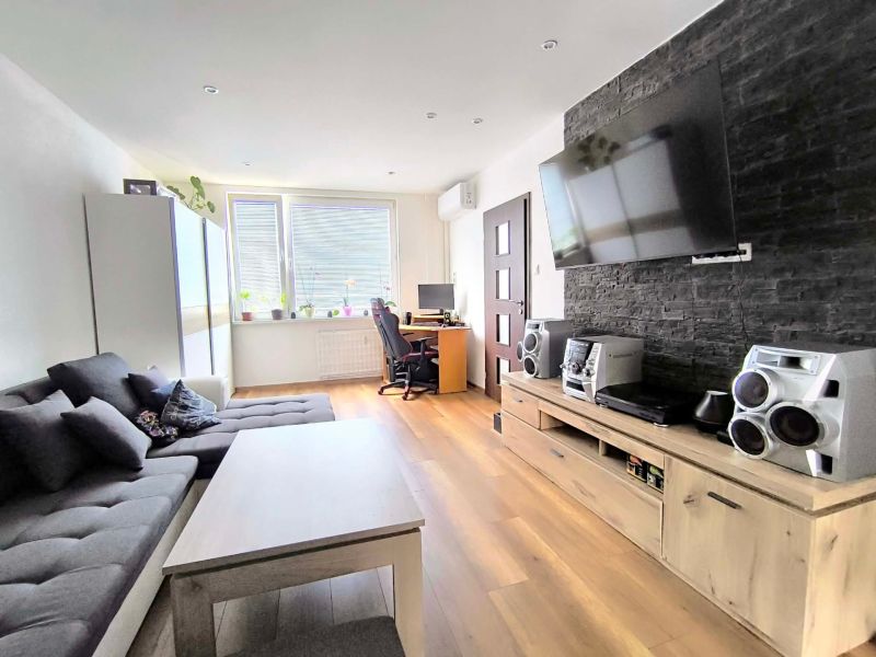 Living room with a sofa, television, and wooden decor flooring in a 3-room apartment.