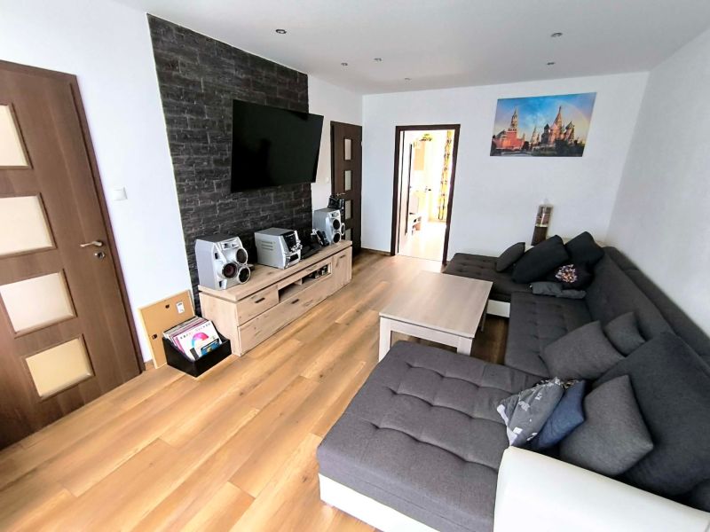 Living room with a sofa and wooden decor flooring in a 3-room apartment.