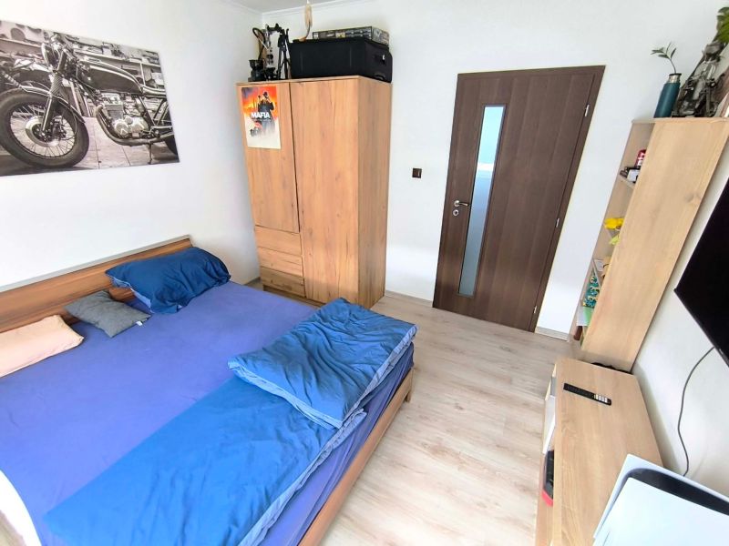 A bedroom in a three-room apartment with a wooden decor floor and furniture.