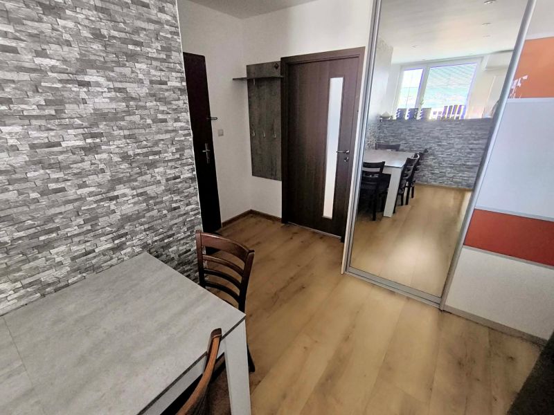 Dining room in a 3-room apartment with a wooden decor floor and a stone wall.