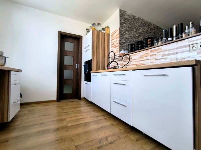 A kitchen in a 3-room apartment with white cabinets and a wood-patterned floor.