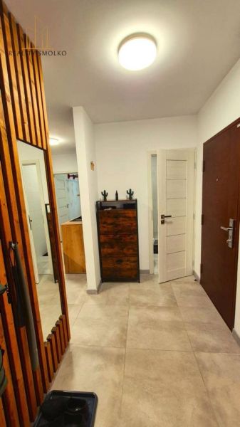 A hallway in a 3-room apartment with tiles, a mirror, and wooden furniture elements.