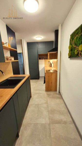 A kitchen in a 3-room apartment with a wood-patterned floor and white walls.