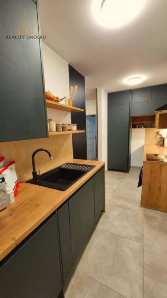 A kitchen in a 3-room apartment with a wood-patterned floor and modern storage space.