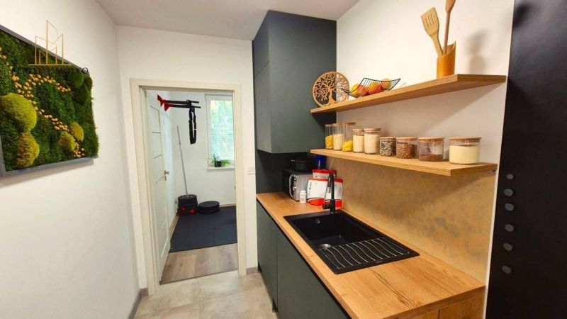Kitchen shelves with food, wooden decor floor, view into the adjacent room.
