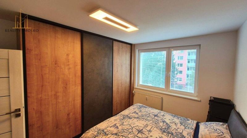Bedroom in a 3-room apartment with a large wardrobe, bed, and window. Floor with wood decor.