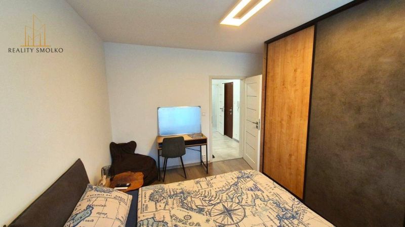 Bedroom with a bed featuring a map pattern, a desk, and a wardrobe in a 3-room apartment.
