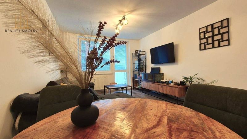 Living room in a three-room apartment with a TV, sofa, and table with decoration.