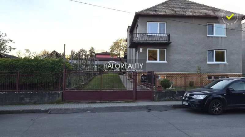 A family house in Poltár with a front garden and a car parked on the street.