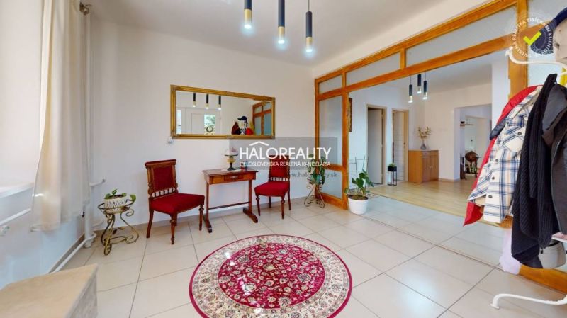 Interior of a family house with red armchairs, a table, and a round carpet.