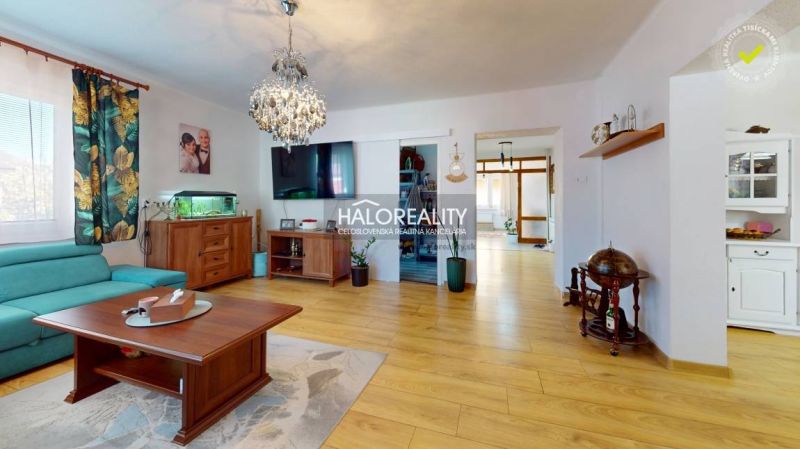 Living room with wood-patterned flooring in a family house, with a sofa and chandeliers.
