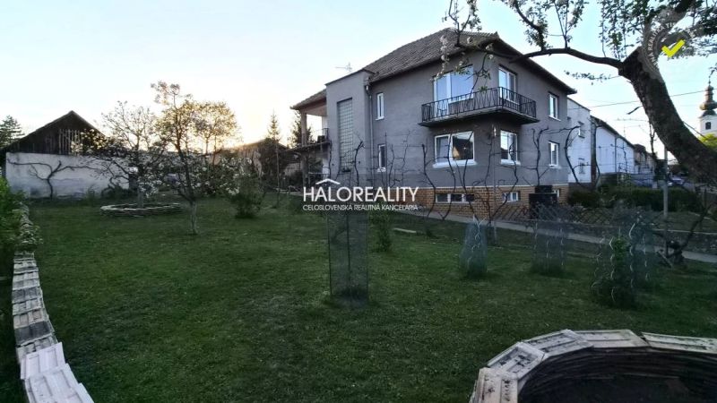 A garden at a family house in Poltár with trees and a lawn.