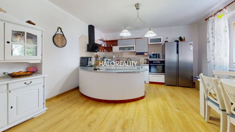 The kitchen in the family house with a wooden decor floor is dominated by white cabinets and appliances.