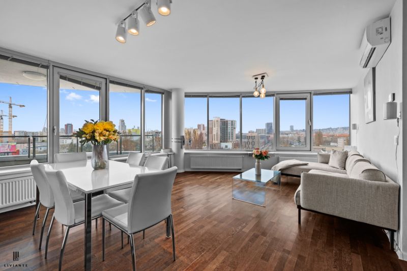 Living room in a 3-room apartment with panoramic windows and a wooden decor floor.