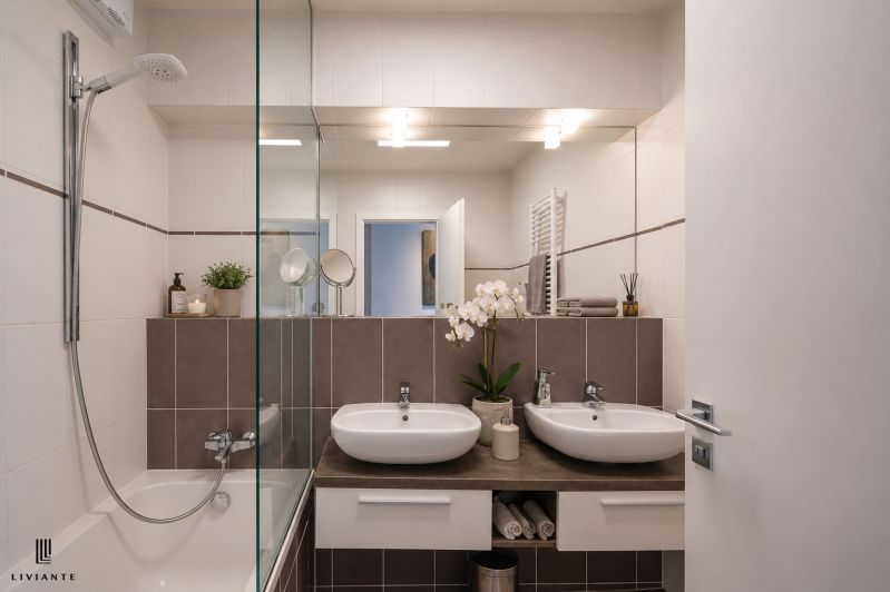 A bathroom with two sinks and a shower in a 3-room apartment, elegant design.