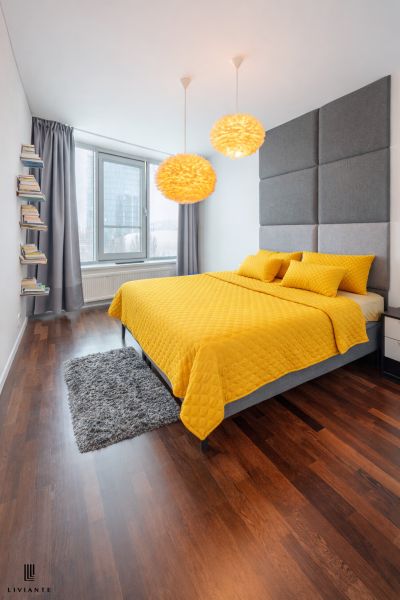 A bedroom in a 3-room apartment with a wooden decor floor and yellow bed linen.