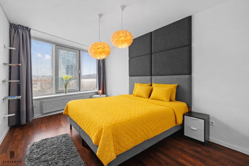 A bedroom in a 3-room apartment with a bed and yellow bedding, a floor with a wooden decor.