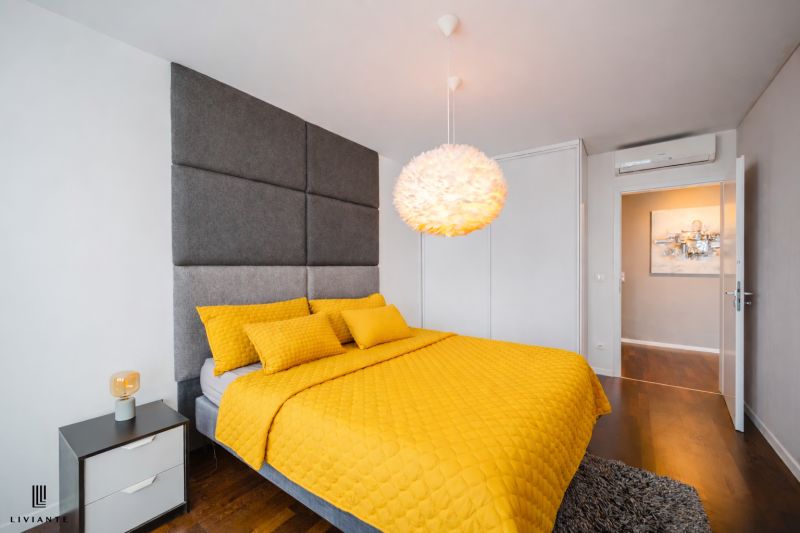 Bedroom in a 3-room apartment with a wooden decor floor and yellow bedding.