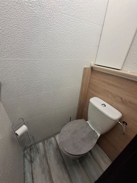 A toilet with a wooden decor on the floor in a 3-room apartment.
