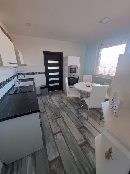 A kitchen with a sophisticated black and white unit and a dining table, 3-room apartment.
