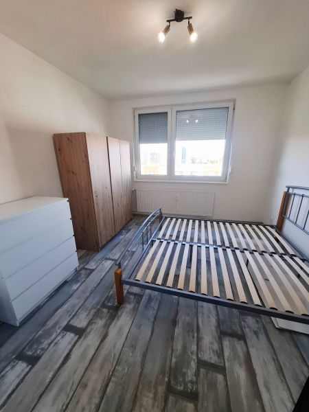 A bedroom with a bed, wardrobe, and wooden decor flooring in a three-room apartment.