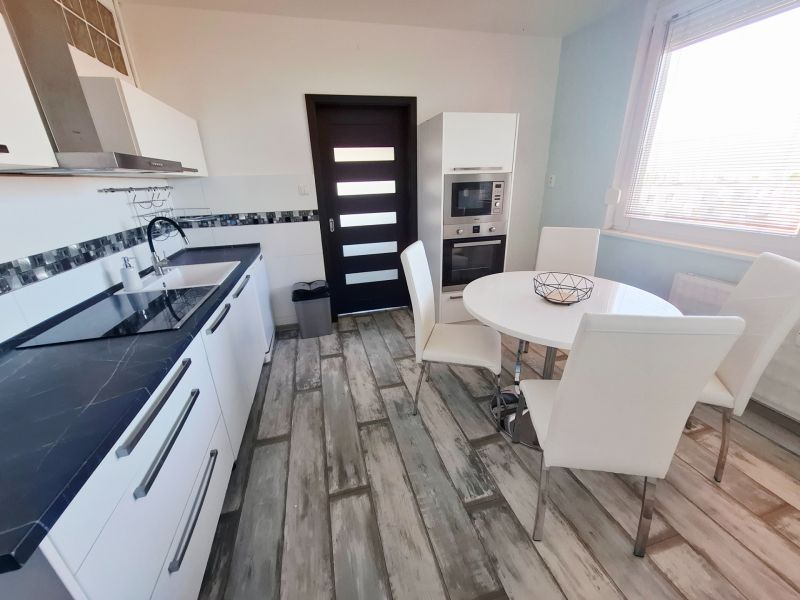 A kitchen in a 3-room apartment with white furniture and a wooden decor floor.