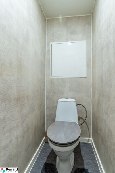 A toilet with a WC bowl and walls with a light texture, 2-room apartment.
