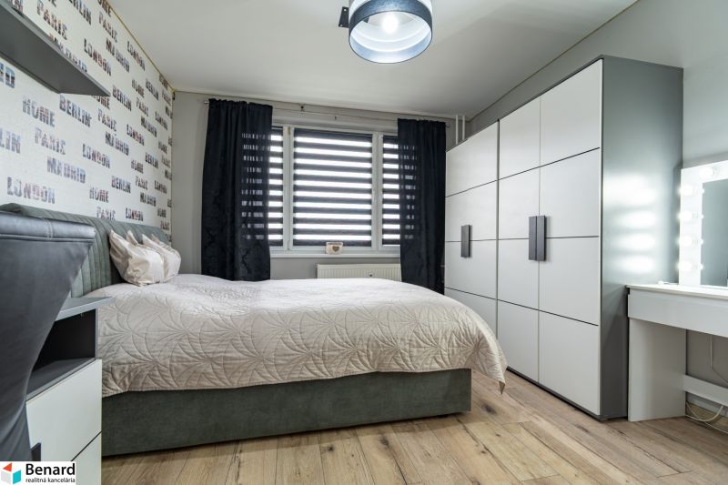 Bedroom in a 2-room apartment with a bed, wardrobe, and floor with wooden decor.