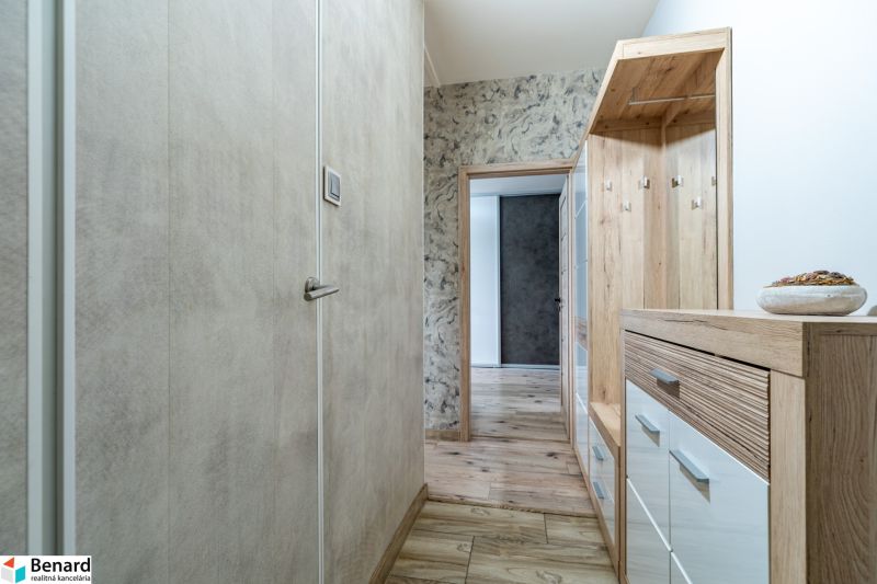 A hallway with furniture and flooring with a wooden decor in a 2-room apartment.