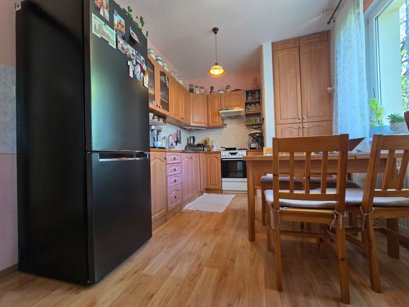 A kitchen in a 2-room apartment with a wooden decor floor and wooden furniture.