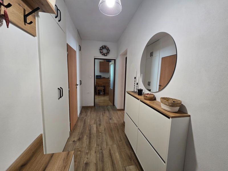 The entrance hall in a 2-room apartment with white furniture and a wooden decor floor.