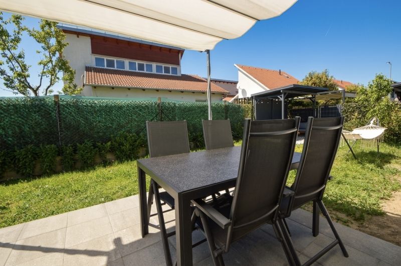 The garden of a family house in Rajka with a terrace, table, chairs, and lawn.