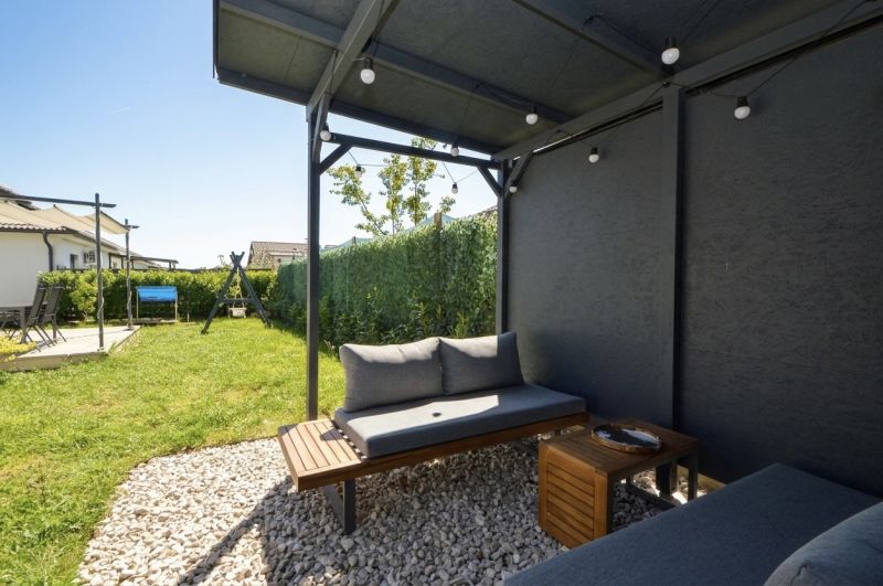 The garden of a family house in Rajka with a seating area under a pergola and a swing.