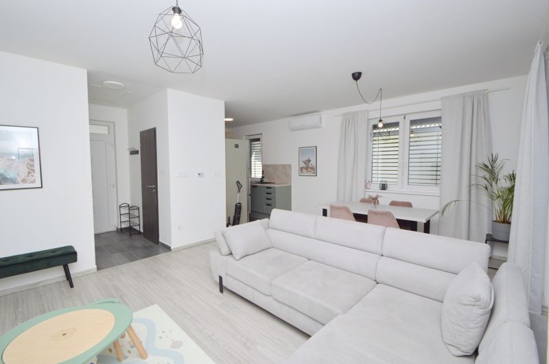 Living room in a family house with a sofa, dining table, and wooden decor flooring.