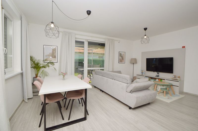 A family house with a wooden decor floor, a sofa, a table, and a television.