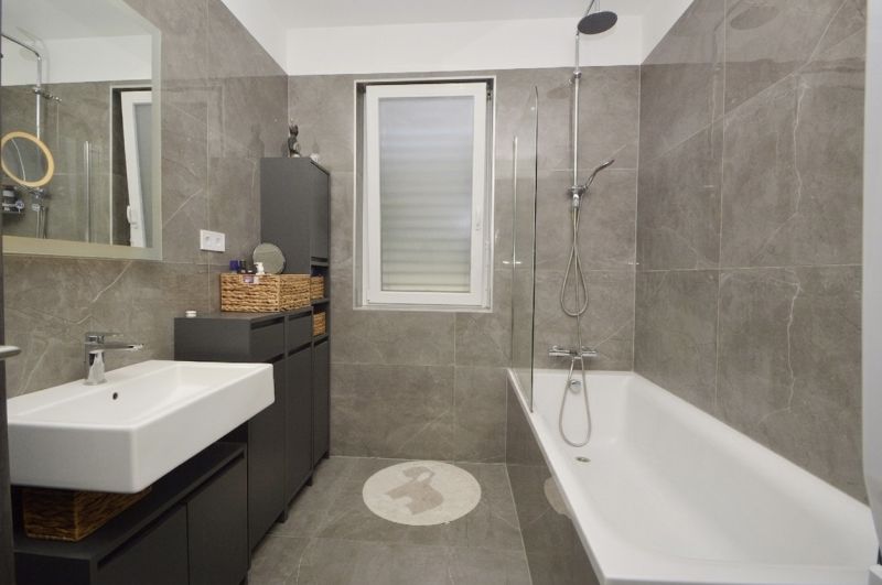 Bathroom with a bathtub and a sink, neutral decor, family house.