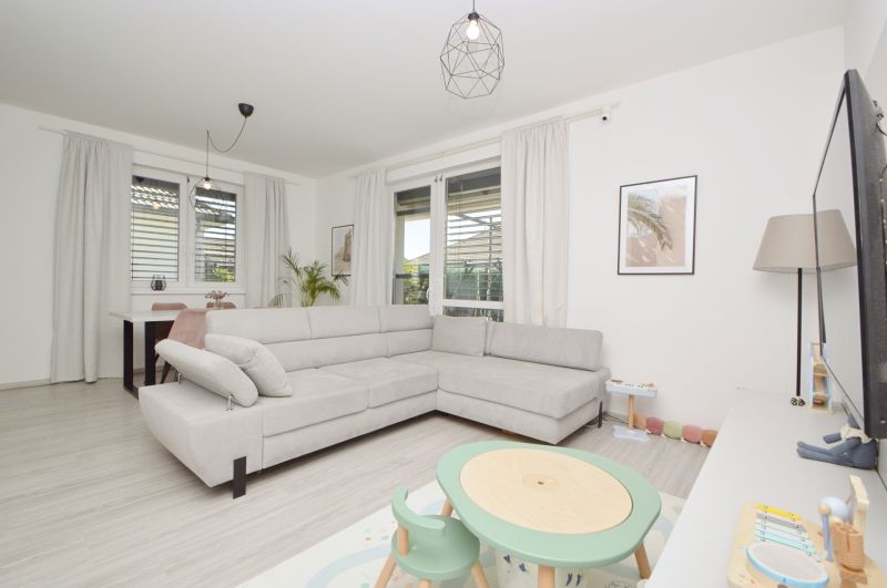 Living room in a family house with a wooden decor floor and a gray sofa.