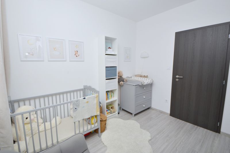 Children's room with a crib, changing table, and wooden decor flooring in a family house.
