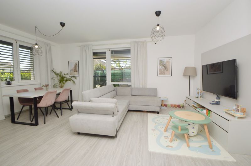 Living room in a family house with a wooden decor floor, a cozy couch, and a gaming corner.