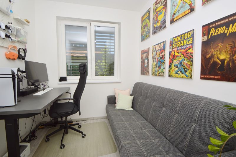 Interior of a family house with a work desk, couch, and comic motifs on the wall.
