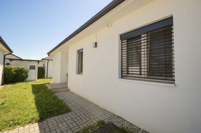 A family house in Rajka with a lawn, paving, and modern shutters.