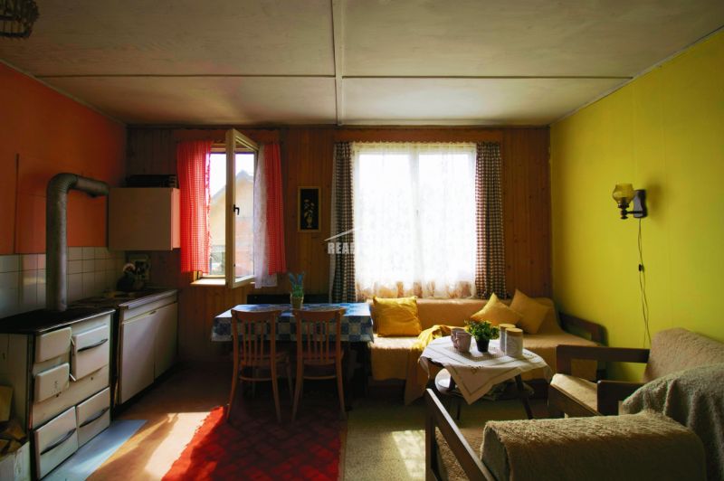 A room in a cottage with wooden decor, afternoon light through the curtains on the window.