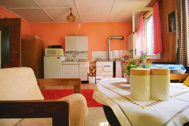 A cozy kitchen in a cottage with a tiled stove and rustic furnishings.