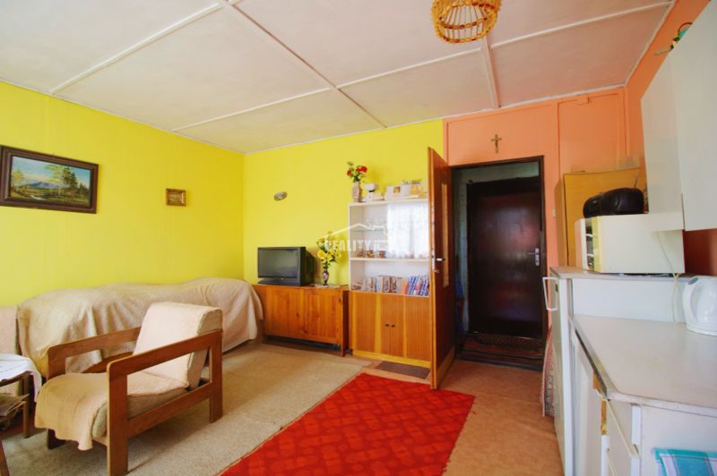 The interior of a cabin with a television, a sofa, and a carpet on a wooden-decorated floor.