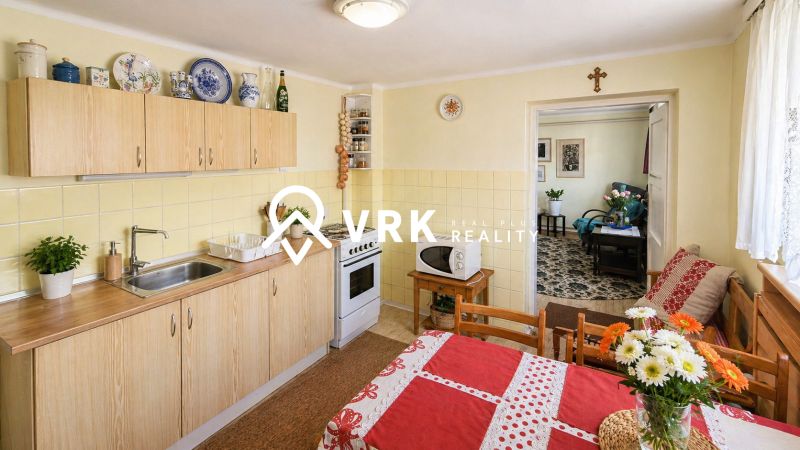 A kitchen in a family house with a dining table, flowers, and kitchen furniture with a wooden decor.