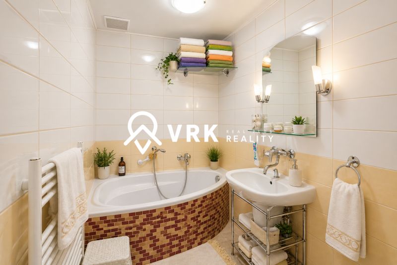 Bathroom in a family house with a bathtub, sink, and storage shelves.